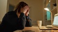 Feeling exhausted. Tired young woman looking at laptop screen, sitting at her working place in the evening at home Royalty Free Stock Photo