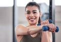 Feeling fit and looking fabulous. Portrait of a young woman working out with dumbbell weights in a gym. Royalty Free Stock Photo