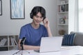 Feeling good happy and positive at work. Young Asian businessman wearing headset on video call with clients on laptop. Royalty Free Stock Photo
