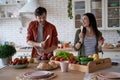 Feeling happy and carefree. Young playful family couple dancing, singing and having fun while preparing healthy food in Royalty Free Stock Photo