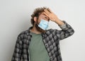 Feeling high temperature young man wearing protective sterile medical mask on his face to protect coronavirus curly hair Royalty Free Stock Photo