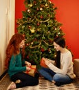 Feeling like kids again. two young women sitting by a Christmas tree and opening their presents. Royalty Free Stock Photo