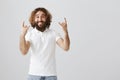 Feeling like rockstar. Portrait of upbeat positive eastern guy with beard and curly hair showing rock gestures and