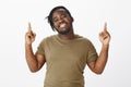 Feeling like winner. Portrait of charming dark-skinned plump man with positive and happy attitude, raising index fingers