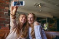 Feeling photogenic. two attractive young girlfriends taking selfies while sitting in a cafe.