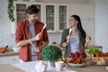 Feeling playful. Young happy family couple, husband and wife having fun while preparing healthy food together in the Royalty Free Stock Photo