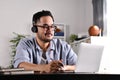 Feeling satisfied and positive at work. Young Asian businessman wearing headset on video call with clients on laptop. Royalty Free Stock Photo