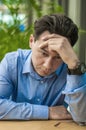 Feeling sick and tired. Frustrated young man keeping eyes closed while sitting at his working place in office. Royalty Free Stock Photo