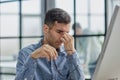 Frustrated young man massaging his nose and keeping eyes closed while sitting at his working place in office Royalty Free Stock Photo