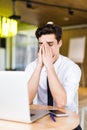 Feeling sick and tired, Frustrated young man massaging his nose and keeping eyes closed while sitting at his working place in offi Royalty Free Stock Photo