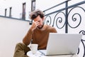 Feeling sick and tired. Frustrated young man massaging his nose and keeping eyes closed while sitting and working on his laptop Royalty Free Stock Photo