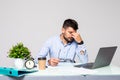 Feeling sick and tired. Frustrated young man massaging his nose and keeping eyes closed while sitting at his working place in Royalty Free Stock Photo