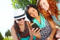 Feeling social. Three teenage girls sitting outside with a cellphone smiling at a text message.