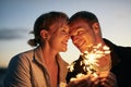 Feeling the spark of new love. a happy young couple playing with sparklers on the beach at sunset.