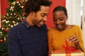 Feeling special on Christmas. a young woman opening her Christmas present while sitting beside her boyfriend.