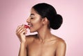 Feeling for strawberries. a beautiful young woman eating a cherry against a pink background. Royalty Free Stock Photo