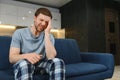 Feeling stressed. Frustrated handsome young man touching his head and keeping eyes closed while sitting on the couch at Royalty Free Stock Photo