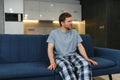 Feeling stressed. Frustrated handsome young man touching his head and keeping eyes closed while sitting on the couch at Royalty Free Stock Photo