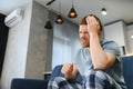 Feeling stressed. Frustrated handsome young man touching his head and keeping eyes closed while sitting on the couch at Royalty Free Stock Photo