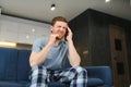 Feeling stressed. Frustrated handsome young man touching his head and keeping eyes closed while sitting on the couch at Royalty Free Stock Photo