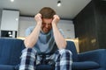 Feeling stressed. Frustrated handsome young man touching his head and keeping eyes closed while sitting on the couch at Royalty Free Stock Photo