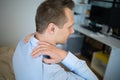 Feeling tired. Back view of frustrated young man looking exhausted and massaging his neck while sitting at workplace