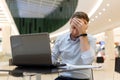 Feeling tired. Frustrated young man covering his face with hands while working on laptop Royalty Free Stock Photo