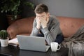 Feeling tired.Frustrated young  man student looking exhausted and covering his face with hands while sitting at laptop Royalty Free Stock Photo