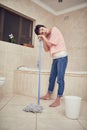 Feeling weary from housework. a tired looking woman mopping a bathroom floor. Royalty Free Stock Photo