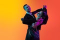 Dynamic portrait of young beautiful man and woman dancing ballroom dance isolated over gradient orange pink background Royalty Free Stock Photo