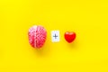 Feelings and mind concept with brain plus heart on yellow background top view