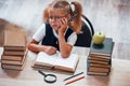 Feels bored and tired. Cute little girl with pigtails is in the library. Apple on the books Royalty Free Stock Photo