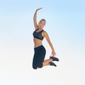 It feels good to be fit. Full length shot of a sporty young woman jumping against a blue sky. Royalty Free Stock Photo