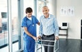 Feels great to be hitting the road to recovery. Portrait of a senior patient with a walker getting assistance from a Royalty Free Stock Photo