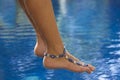 Feet with ankle bracelet above the pool Royalty Free Stock Photo