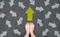 Feet and Arrows on Road. Woman Bare Feet with Gray Nail Polish Manicure Standing on Grunge Concrete with Many White Arrow Sign and Royalty Free Stock Photo