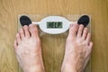 Feet on a bathroom scale with the word HELP on the screen. Lose weight concept with person on a scale measuring kilograms Royalty Free Stock Photo