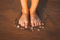 Feet on a beach with cockleshells Royalty Free Stock Photo