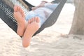 Feet of a beautiful woman. She lies in a hammock on the beach of the sea. In the summer she feels the good weather. she is on Royalty Free Stock Photo