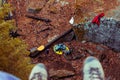 Feet in boots hang from a high cliff overlooking the autumn forest. First-person view