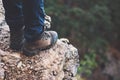 Feet boots on rocky cliff with forest aerial view