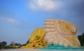 Feet of Buddha with yellow robe covering the legs against blue sky background