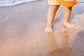 Feet of child boy touching water and standing on beach