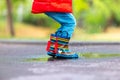 Feet of child in colorful rubber rain boots jumping over rainy puddle in a park Royalty Free Stock Photo