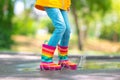 Feet of child in colorful rubber rain boots jumping over rainy puddle in a park Royalty Free Stock Photo