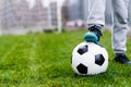 Feet of child on football / soccer ball on grass Royalty Free Stock Photo