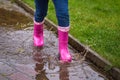 Feet of a child in pink rubber boots jumping through a puddle in the rain, splashing drops Royalty Free Stock Photo