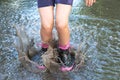 Feet of child in rubber boots jumping over a puddle and water splashes Royalty Free Stock Photo