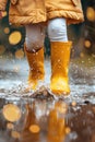 Feet of child in yellow rubber boots jumping over a puddle in the rain Royalty Free Stock Photo