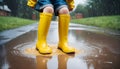 Feet of child in yellow rubber boots jumping over puddle in rain Royalty Free Stock Photo